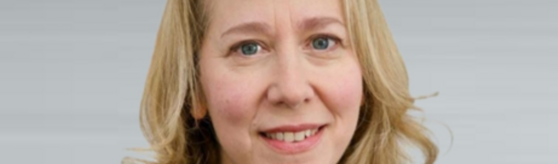 Professional headshot of a blonde woman smiling slightly.