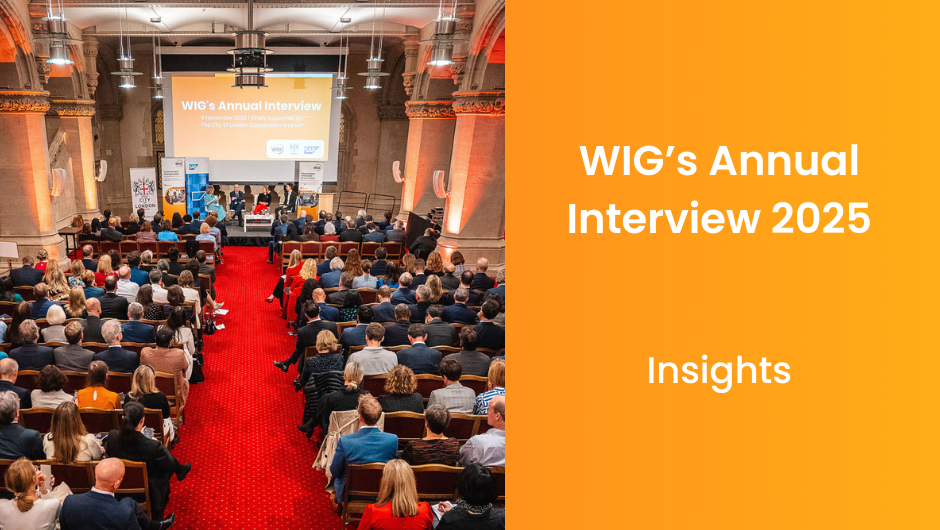 Audience seated in a historic hall for the WIG Annual Interview, with panellists on stage.