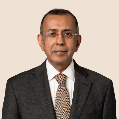 Professional portrait of a man in a grey suit and patterned tie.