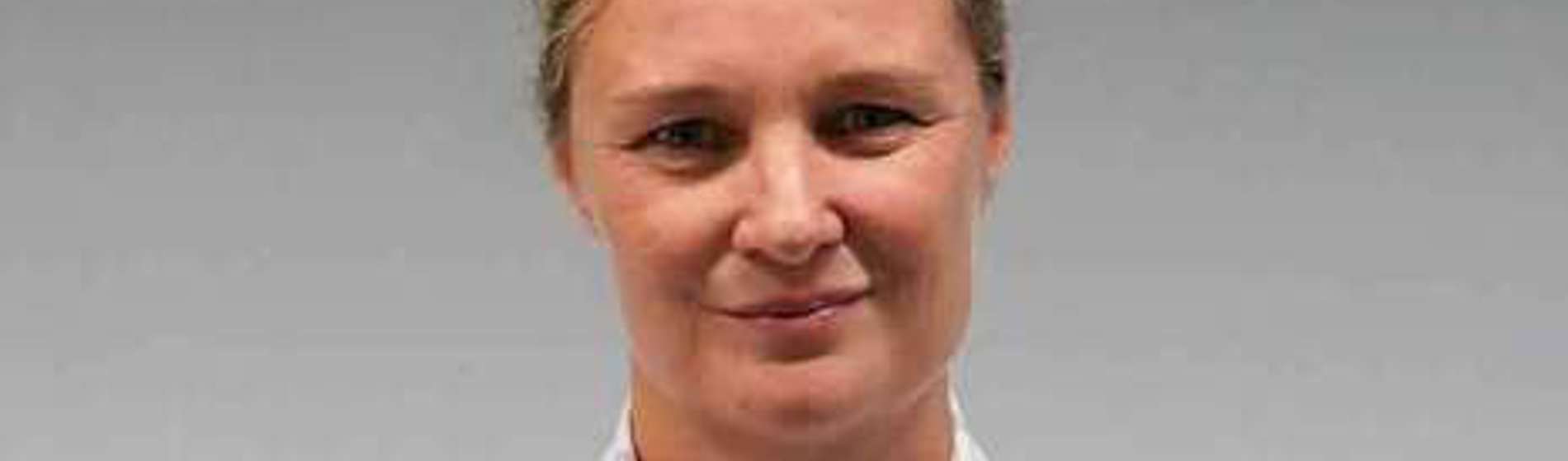 Blonde woman in a white patterned shirt, professional headshot.
